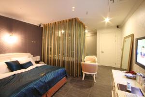 ein Schlafzimmer mit Bett, Schreibtisch und Fernseher in der Unterkunft WIZ Hotel in Paju