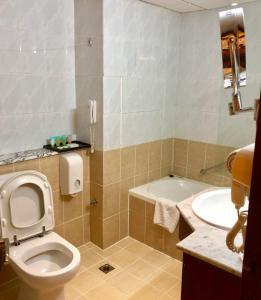 a white toilet sitting next to a sink in a bathroom at Ajman Beach Hotel in Ajman 