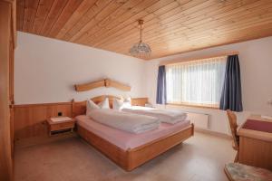 a bedroom with a large bed with a wooden ceiling at Chasa Plajet in Ramosch