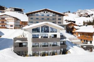 budynek na szczycie pokrytej śniegiem góry w obiekcie Hotel Bergkristall Oberlech w Lech am Arlberg