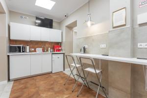 a kitchen with white cabinets and a bar with stools at Babel Hostel in Wrocław