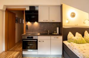 オエッツにあるSternenvillaの白いキャビネット付きのキッチン、ベッド1台が備わる客室です。