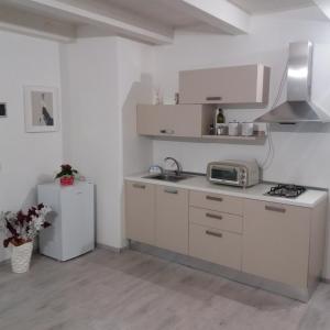 a kitchen with white cabinets and a microwave and a refrigerator at La Corte di Aci in Acireale