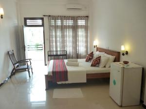 1 dormitorio con 1 cama y nevera. en Hotel Ocean View Cottage, en Hikkaduwa