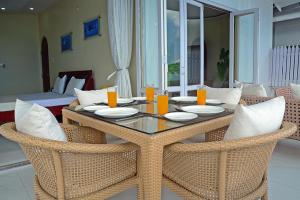 
a dining room table with two chairs and a glass of orange juice at Kokari Guesthouse in Port Blair
