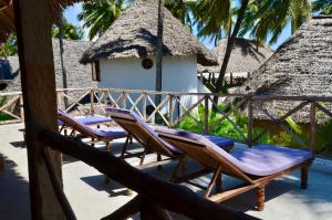 two lounge chairs on a porch with a thatch roof at Amka Guest house in Jambiani