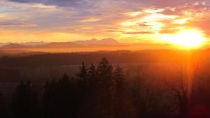 un coucher de soleil avec le soleil dans le ciel et les arbres dans l'établissement Berghotel Jägerhof ****S, à Isny im Allgäu