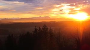 einen Sonnenuntergang mit der Sonne am Himmel und Bäumen in der Unterkunft Berghotel Jägerhof ****S in Isny im Allgäu