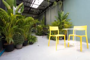 two yellow chairs and a table and some plants at The Orientale Hostel in Bangkok