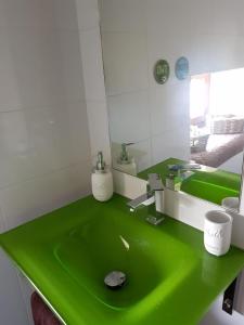 La salle de bains est pourvue d'un lavabo vert et d'un miroir. dans l'établissement Elteixorural, à Teijois