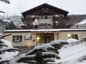 Una casa nella neve con un albero di Natale di Residence Casa Federica a Valfurva
