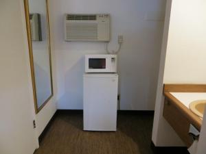 a small room with a microwave on top of a refrigerator at Cameo Motel - Portland in Portland