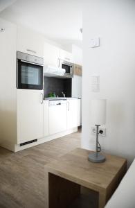 a kitchen with white cabinets and a table with a lamp at Adapt Apartments Giessen in Gießen
