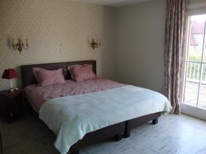 um quarto com uma cama com almofadas cor-de-rosa e uma janela em Villa Donnylaan em De Panne