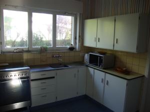 uma cozinha com armários brancos, um lavatório e um micro-ondas em Villa Donnylaan em De Panne