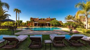 una piscina con sillas y una casa en L'OLIVERAIE DE L'ATLAS, en Marrakech