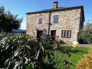 una antigua casa de piedra con un jardín delante de ella en Apartamentos rurales Casa Do Cabo en Vega de Logares