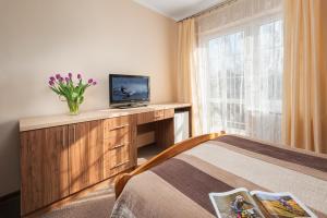 Un dormitorio con una cama y un televisor y una ventana. en RizaVilla, en Krynica Morska