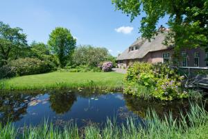 an old house with a pond in front of it at Giethoorn Lodge in Giethoorn