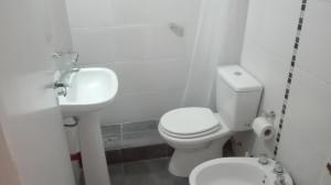 a white bathroom with a toilet and a sink at Hotel Caribe in Mar del Plata