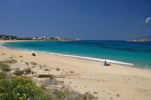 a person sitting on a beach near the water at Viglaki House in Naxos Chora
