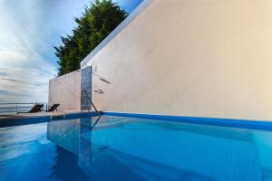 a swimming pool next to a white wall at Calheta Holiday Houses in Arco da Calheta