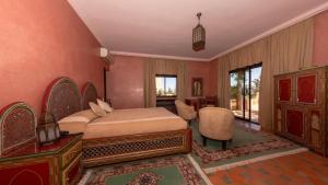 una camera con letto, tavolo e sedie di L'OLIVERAIE DE L'ATLAS a Marrakech