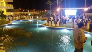 a group of people standing around a swimming pool at night at Condomínio Solarium Residence in Aquiraz