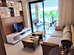 a living room with a couch and a tv at Apartamento Alto Padrão 3 quartos Iberostate Praia do Forte in Praia do Forte