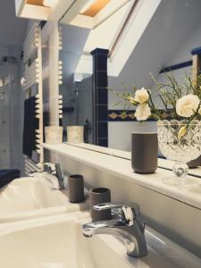 a bathroom sink with a mirror and a vase of flowers at Postwirt Annaberg in Annaberg im Lammertal