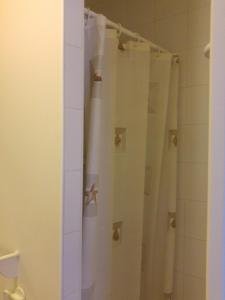 um chuveiro com uma cortina de chuveiro branca na casa de banho em Le Relais de Montchat em Lyon