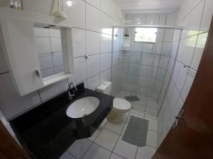 a white bathroom with a sink and a toilet at Casa em Bombinhas in Bombinhas
