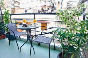 een kleine tafel en stoelen op een balkon met planten bij Luxury apartment near Acropolis! in the Heart of Athens! in Athene
