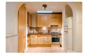- une cuisine avec des placards en bois et un réfrigérateur blanc dans l'établissement The Pink House, à Londres