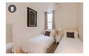 two beds in a room with white walls at The Pink House in London