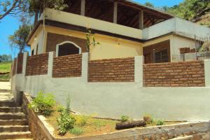 a house with a brick wall and stairs in front of it at Suíte com cozinha em Ibitipoca in Conceição da Ibitipoca