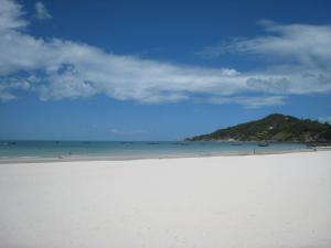 a beach with the ocean and a hill in the background at Tommy Resort in Haad Rin