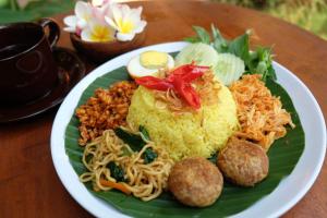 a plate of food with noodles and meatballs on a table at D'Pande Kuta in Kuta