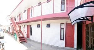 un edificio blanco con una puerta roja en una calle en Hostal Maipu Street, en Punta Arenas