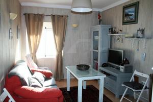 Una sala de estar con un sofá rojo y un televisor. en Don Pelayo, en Barbate