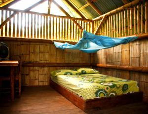 a bed in a wooden room with a hammock at Maracumbo Lodge in Mompiche