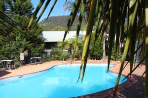 una gran piscina azul con mesa y sillas en Kangaroo Valley Golf and Country Retreat en Kangaroo Valley