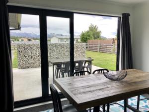 a patio with tables and chairs and a large window at Townhouse Feel in Irishman in Twizel