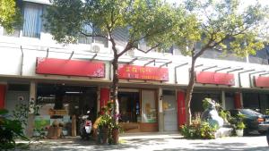 un magasin avec des panneaux rouges à l'avant d'un bâtiment dans l'établissement Miaoli Sanyi Travelling Homestay, à Sanyi