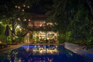 a house with a swimming pool at night at Sambor Village Hotel in Kompong Thom