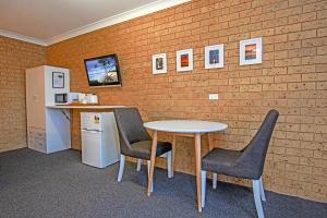a room with a table and two chairs and a brick wall at Coast Inn Motel in Ballina