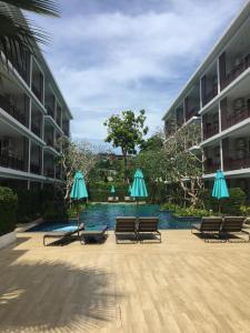 a courtyard with chairs and umbrellas and a pool at Apartments in The Title Beach Rawai in Rawai Beach