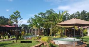 un patio trasero con piscina, sombrilla y columpios en Fuga Village BeachGetaway, en Melaka