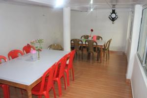 une salle à manger avec des tables blanches et des chaises rouges dans l'établissement Vamoose Olive Homestay Aritar, à Aritar