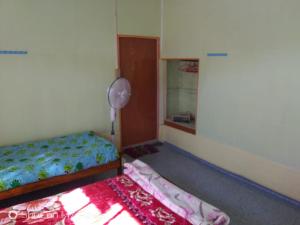 a small bedroom with a bed and a fan at Vamose Hlunbuang in Zuchhip